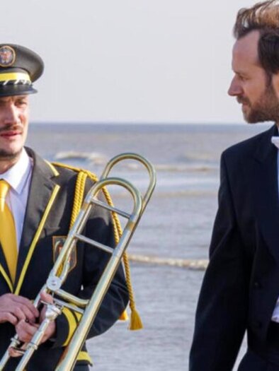 Two men in uniform and tailcoats with trombone by the sea, scene from a musical film. | © Thibault Grabherr