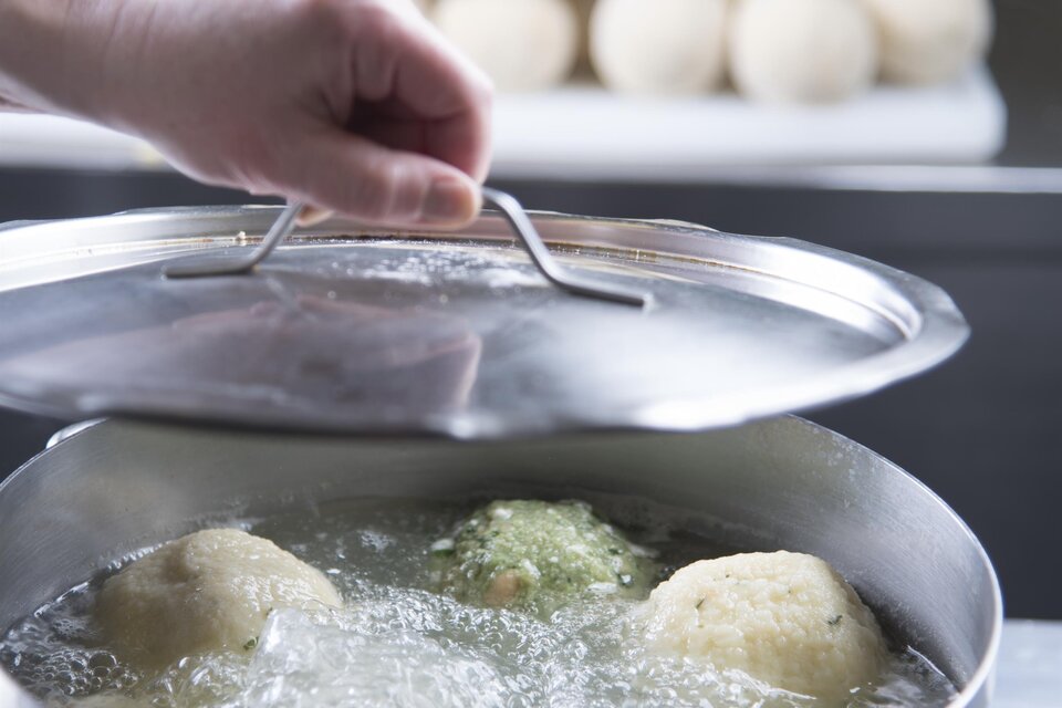 Ein Topf mit kochendem Wasser und mehreren Klößen wird zubereitet. Im Hintergrund sind eine Gruppe von Klößen sichtbar. | © Bernhard Bergmann
