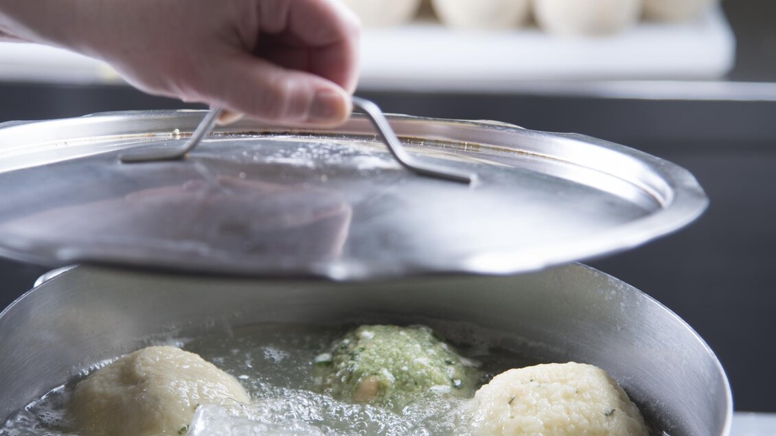 Ein Topf mit kochendem Wasser und mehreren Klößen wird zubereitet. Im Hintergrund sind eine Gruppe von Klößen sichtbar. | © Bernhard Bergmann