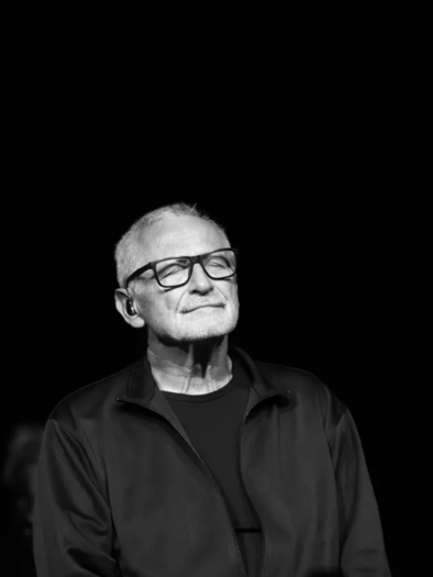 An older man with glasses stands in a dark room, with a thoughtful expression. The lighting highlights his face and creates a calm atmosphere. | © ©Thomas Steinborn