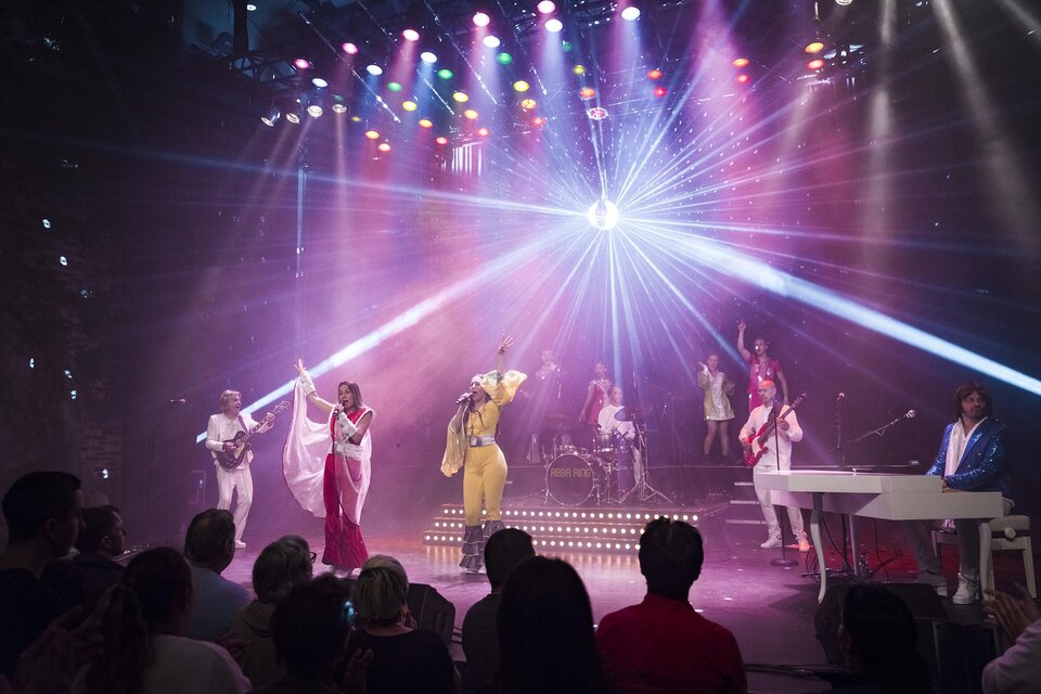 Eine lebhafte Bühnenaufführung mit mehreren Musikern und bunten Lichtern. Die Künstler präsentieren eine dynamische Show mit Gesang und Tanz. | ©  Pura Vida Theater und Musical GmbH