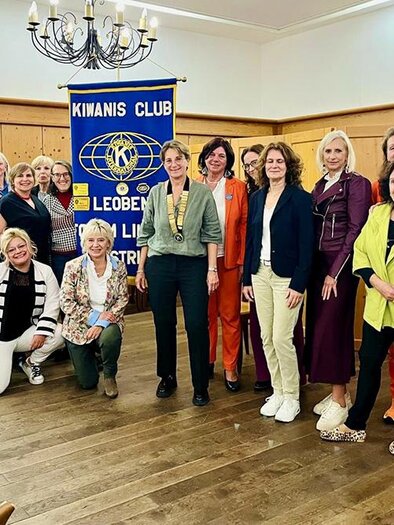 A group of women gathers in a room in front of a Kinanis Club banner. They are wearing a variety of colorful outfits and smiling kindly at the camera. | ©  Kiwanis Club Leoben Forum Liuben
