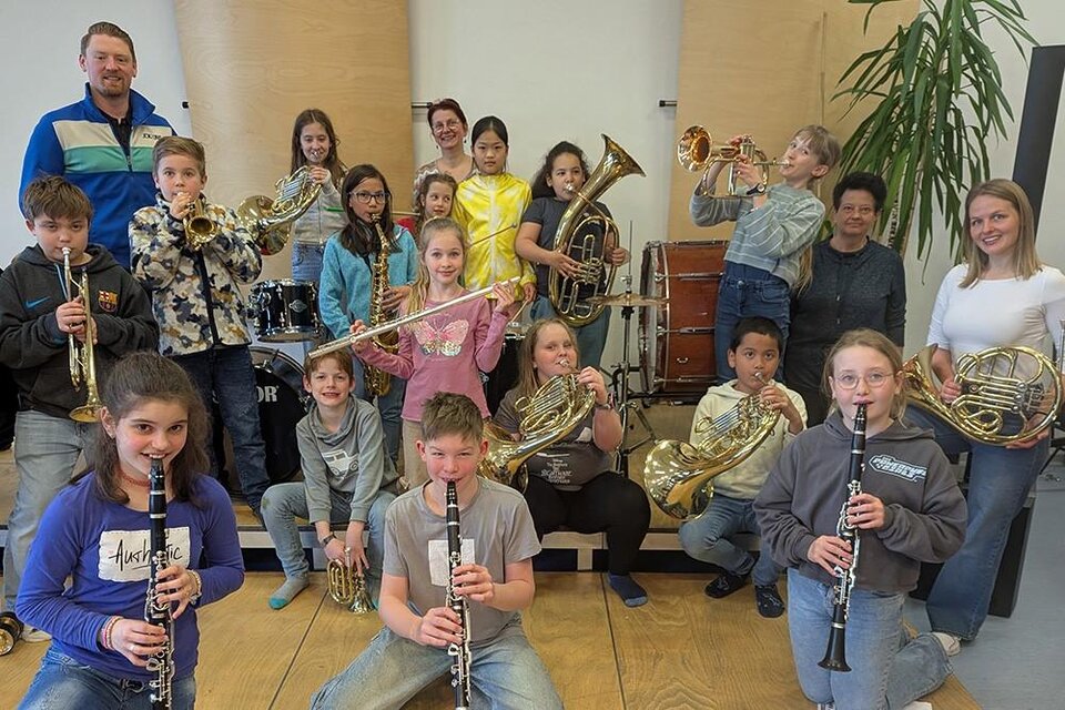 Eine Gruppe von Kindern und Jugendlichen steht lächelnd mit verschiedenen Musikinstrumenten in einem Raum. Im Hintergrund sind Schlagzeug und weitere Instrumente sichtbar. | ©  Musik- und Kunstschule Leoben