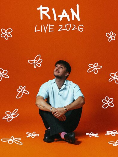 Ein junger Mann sitzt nachdenklich vor einem orangefarbenen Hintergrund, umgeben von einfachen Blumenzeichnungen. Der Text „RIAN LIVE 2026“ steht oben im Bild. | © (c)Mario Wallner.