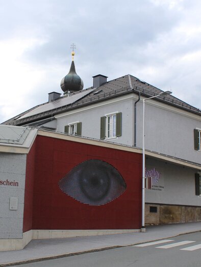 A building with a large, artistic eye motif on the wall. The architecture is modern and the surroundings are quiet. | © TV Südsteiermark - Irene Löschnig