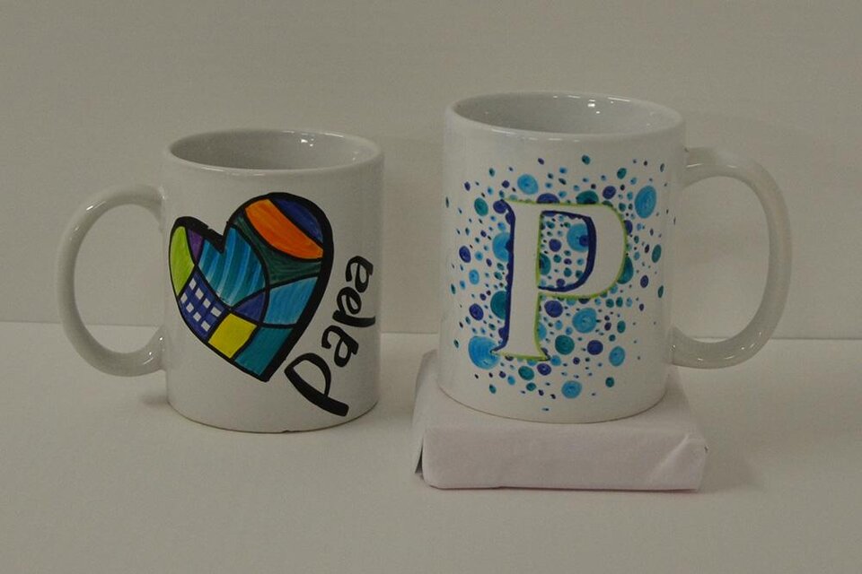 Zwei Tassen sind auf einem Tisch platziert. Die linke Tasse hat ein buntes Herzdesign, während die rechte Tasse mit blauen Punkten und einem großen Buchstaben "P" verziert ist. | ©  KulturQuartier Leoben