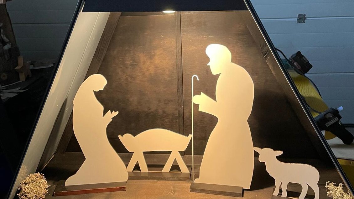 Eine Weihnachtskrippe mit stilisierten Figuren von Maria, Josef, einem Kind in der Krippe und einem Schaf. Die Szene ist beleuchtet und in einem Zeltdesign präsentiert. | © Marktgemeinde Halbenrain