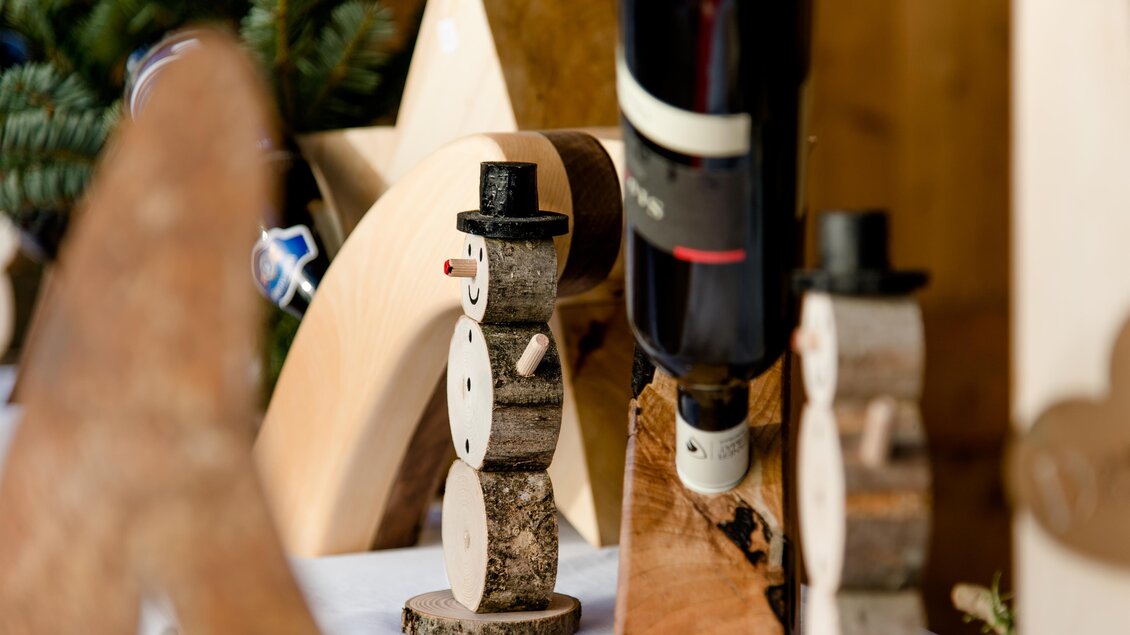 Eine stilvolle Weihnachtsdekoration mit Holz-Schnitzereien, darunter kleine Schneemänner. Im Hintergrund sind weitere hölzerne Formen zu sehen. | © TV Region Graz-Mias Photoart