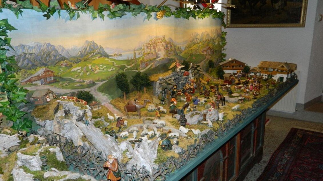 Eine detaillierte Krippe mit Figuren und Landschaftselementen. Im Hintergrund sind Berge, Wiesen und Bauernhöfe zu sehen. | © Birgit Schretthauser