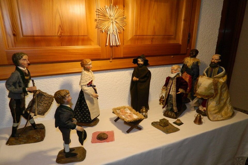 Eine traditionelle Krippe mit handgefertigten Figuren, die eine biblische Szene darstellen. Die Figuren sind auf einem Tisch angeordnet und umgeben von einer Holzdekoration. | © Birgit Schretthauser
