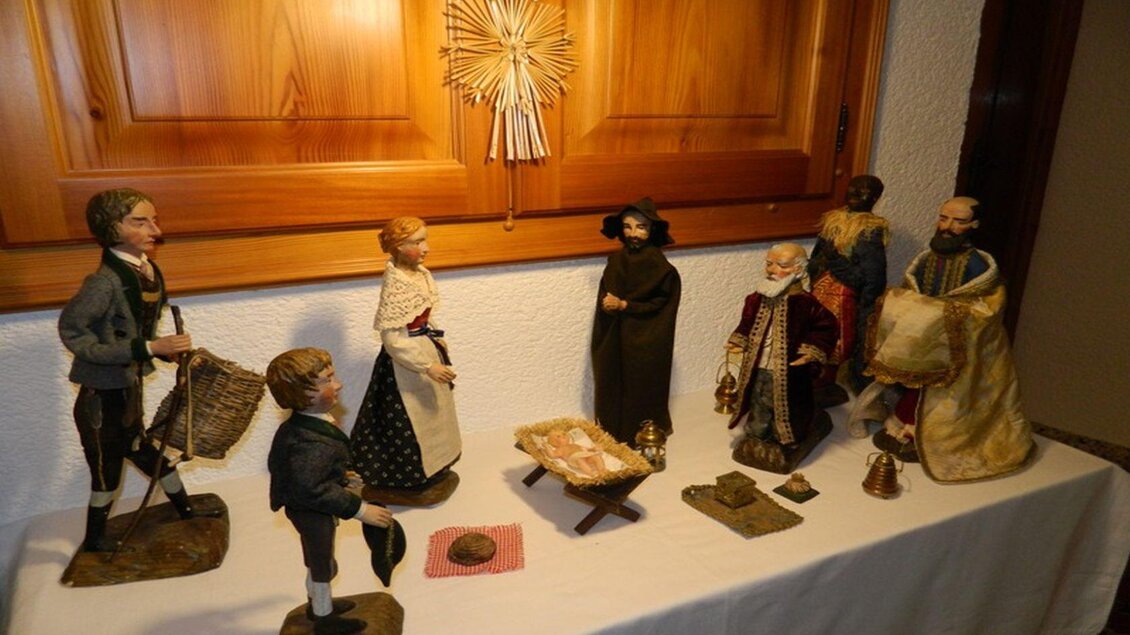 Eine traditionelle Krippe mit handgefertigten Figuren, die eine biblische Szene darstellen. Die Figuren sind auf einem Tisch angeordnet und umgeben von einer Holzdekoration. | © Birgit Schretthauser