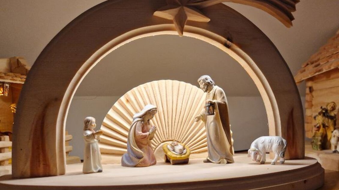 Eine Krippe mit Holzfiguren zeigt die Geburt Jesu. Maria, Josef, das neugeborene Kind und einige Tiere sind umgeben von einer schönen, gestalteten Kulisse. | © Adi Barazutti