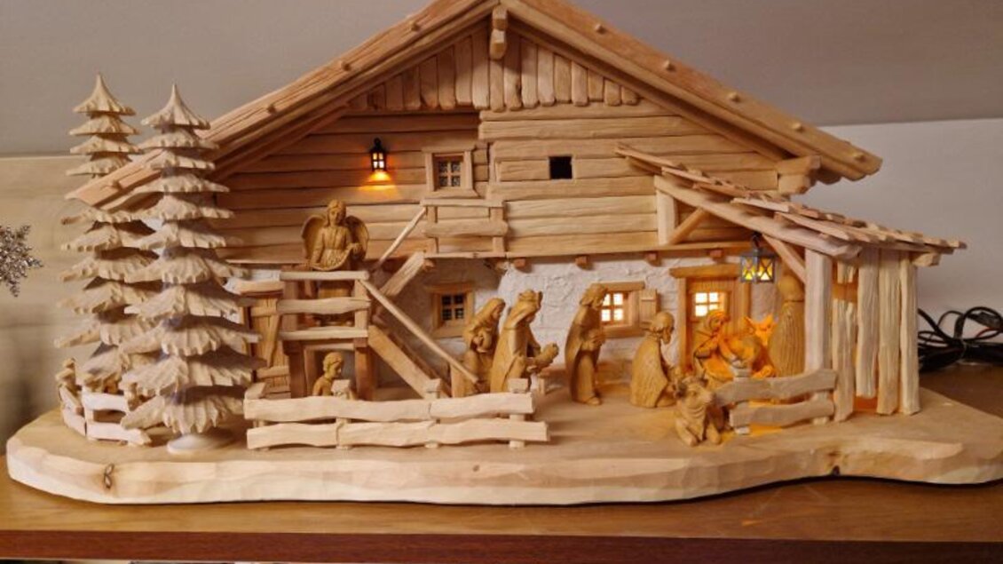 Ein detailreiches Holzmodell eines traditionellen Hauses mit Figuren und Bäumen. Das Modell ist kunstvoll gestaltet und hat eine warme, einladende Atmosphäre. | © Adi Barazutti