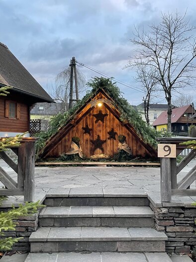 A cozy wooden cabin with green fir branches on the roof stands in the foreground. Special Christmas decorations and surrounding fir trees create a festive atmosphere. | © TV Südsteiermark