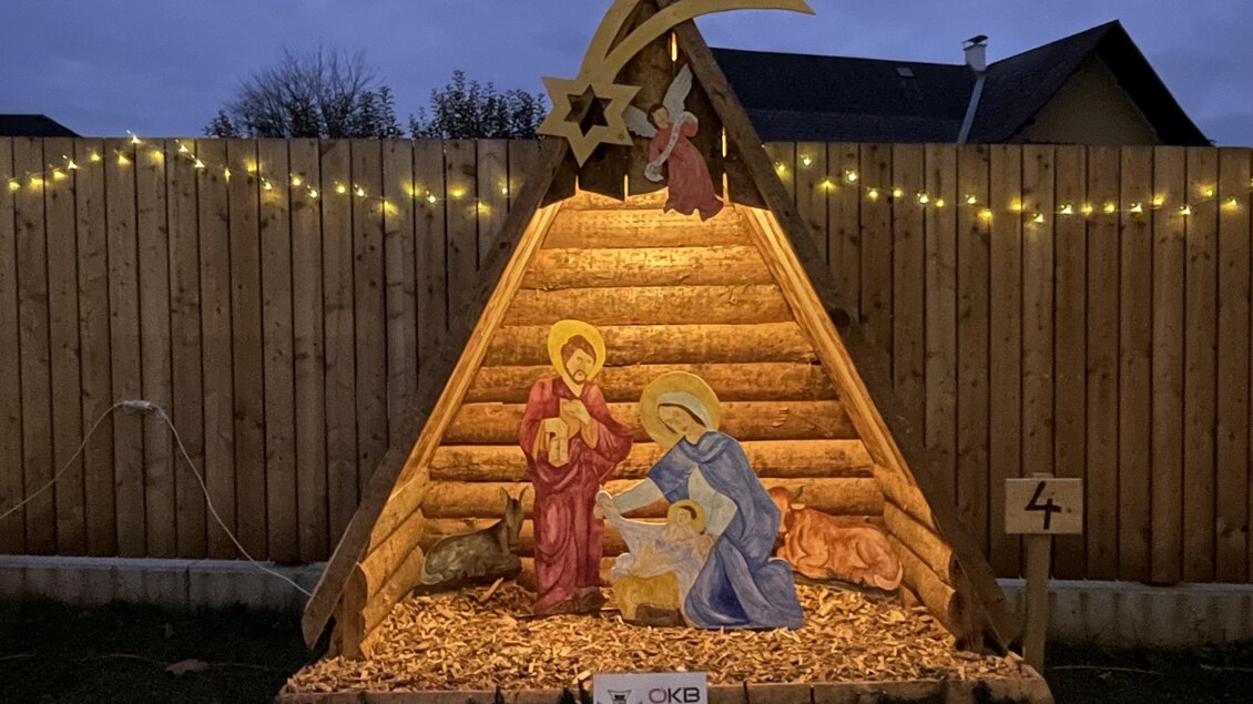 Eine beleuchtete Krippe mit Maria, Josef und dem neugeborenen Jesus in einem festlich geschmückten Stall. Im Hintergrund leuchten Lichter und ein Stern ist sichtbar. | © TV Südsteiermark