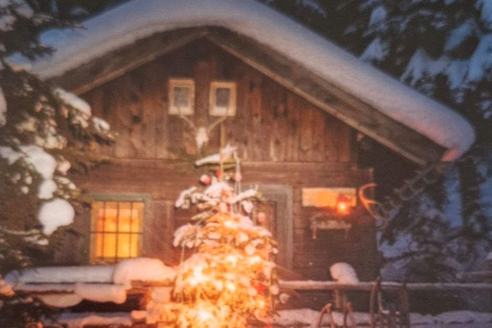 Eine gemütliche Berghütte im Schnee, beleuchtet von warmem Licht. Vor der Hütte steht ein geschmückter Weihnachtsbaum. | © Kumitzer Kulturrausch
