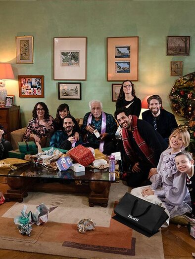 A cheerful family sits in a festively decorated room around a decorated Christmas tree. Gifts are on the table and the atmosphere is celebratory together. | ©  Luna Film