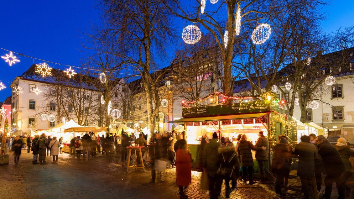 Ein festlicher Weihnachtsmarkt mit vielen Besuchern. Bunte Lichter und Stände schaffen eine gemütliche Atmosphäre. | © Graz Tourismus - Harry Schiffer