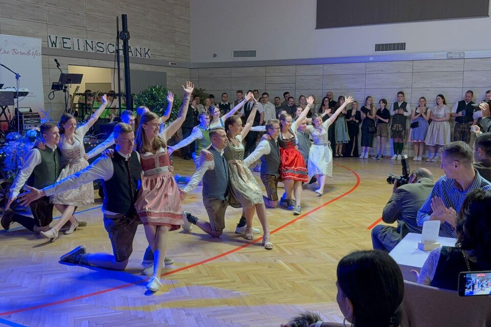 Eine Gruppe von Tänzern in traditionellen Kleidern führt eine Aufführung auf einer Bühne durch. Die Zuschauer klatschen begeistert und genießen die Darbietung. | © Landjugend Bad Blumau