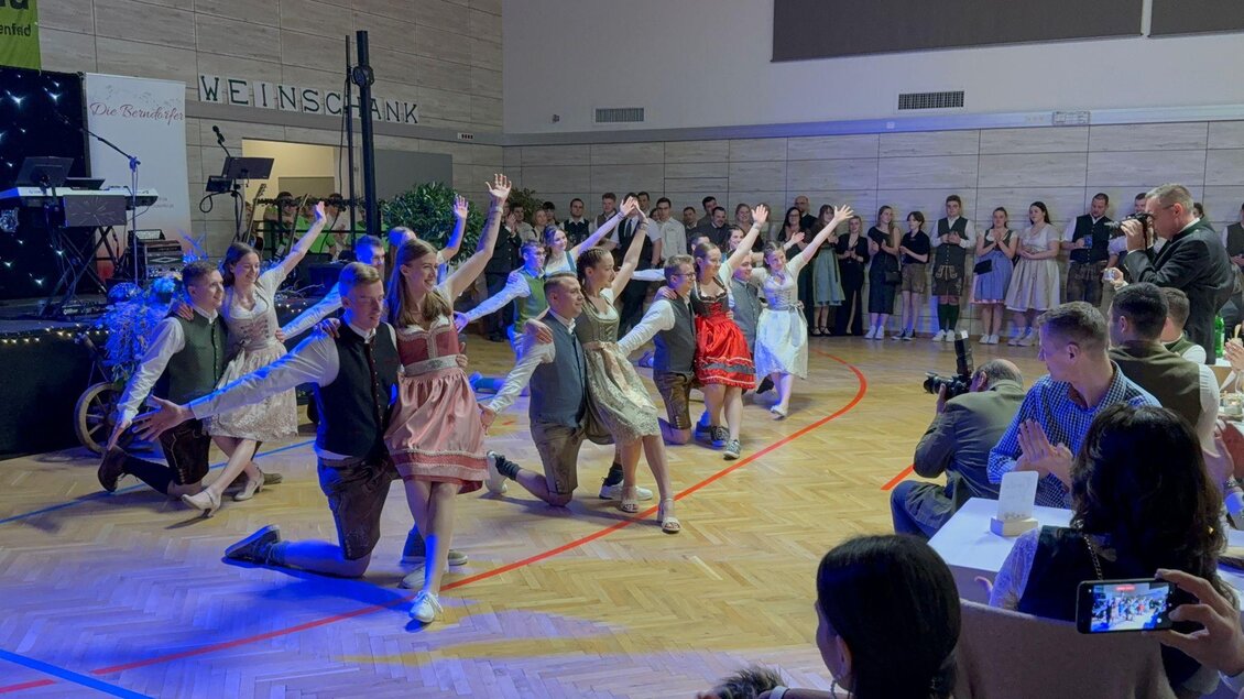 Eine Gruppe von Tänzern in traditionellen Kleidern führt eine Aufführung auf einer Bühne durch. Die Zuschauer klatschen begeistert und genießen die Darbietung. | © Landjugend Bad Blumau