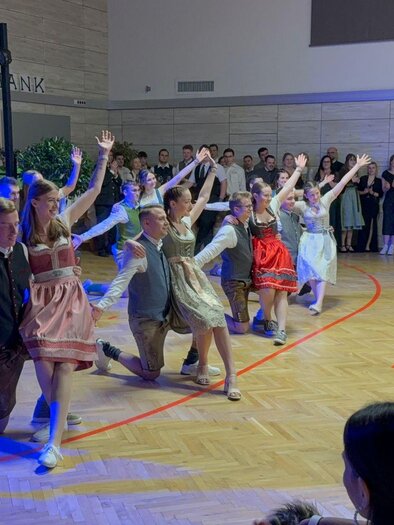 A group of dancers in traditional costumes performs on a stage. The audience claps enthusiastically and enjoys the performance. | © Landjugend Bad Blumau
