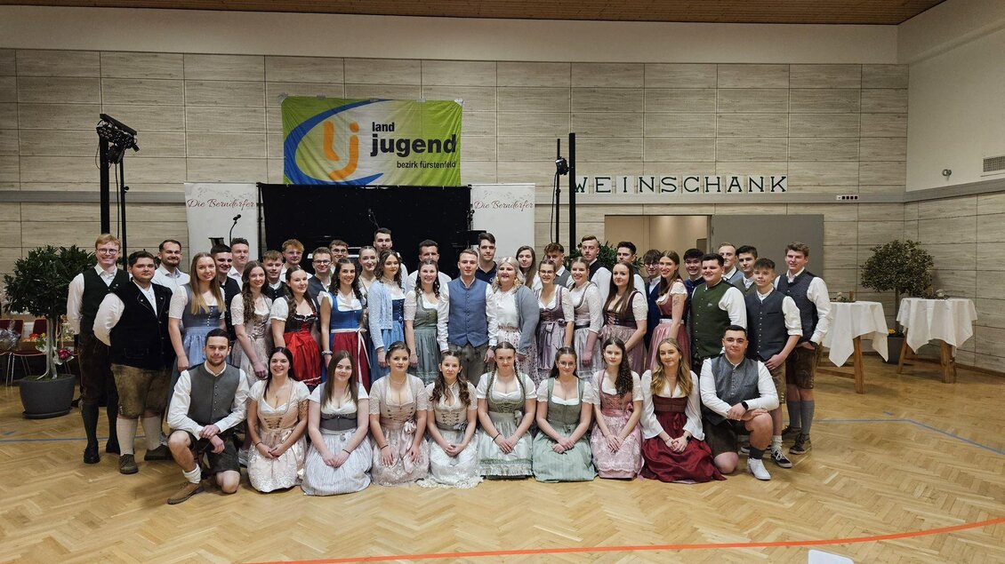 Eine Gruppe von jungen Menschen steht in traditioneller Kleidung zusammen. Im Hintergrund ist ein Banner mit der Aufschrift „Jugend“ zu sehen. | © Landjugend Bad Blumau