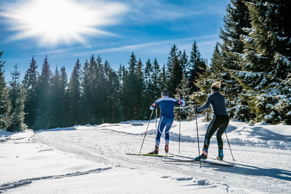 Ein Mann und eine Frau skaten auf der frisch präparierten Langlaufloipe auf der Hebalm, bei Sonnenschein und Neuschnee.  | © Region Graz-Mias Photoart