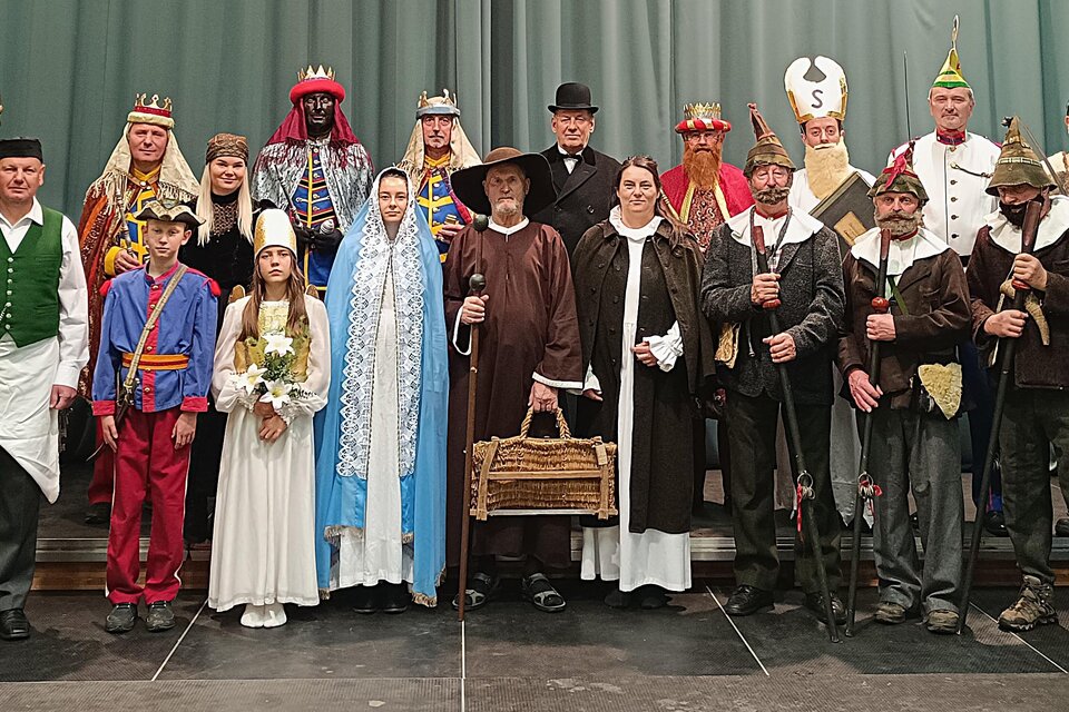 Eine Gruppe von Menschen in traditioneller Kleidung steht auf einer Bühne. Sie lächeln und posieren für das Foto, während sie verschiedene historische oder festliche Charaktere darstellen. | © Tv Murau
