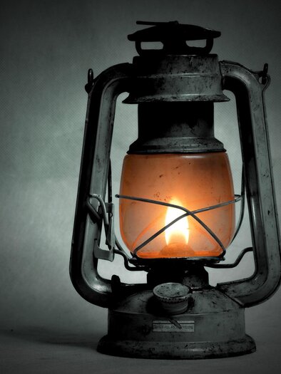 An old lantern with orange glass glows softly. It stands against a dark background and conveys a nostalgic atmosphere. | © pixabay