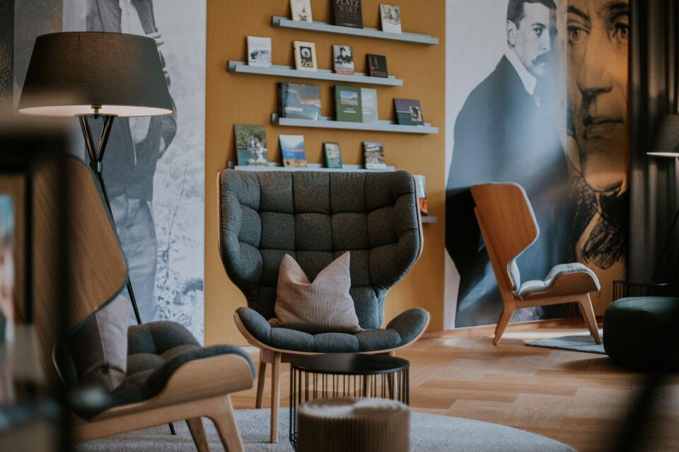 Ein stilvoller Raum mit modernen Möbeln und einer Bücherregalwand. Im Hintergrund sind Schwarz-Weiß-Bilder von historischen Persönlichkeiten zu sehen. | © Lounge (c) Wasnerin, Bad Aussee