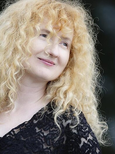 A woman with curly blonde hair is smiling kindly. She is wearing a black top and seems to be relaxed. | ©  Kanizaj Marija