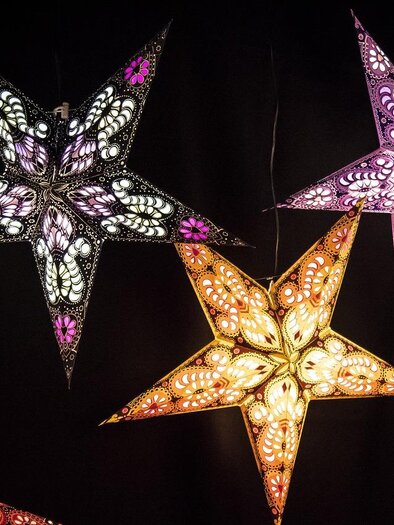 Colorful, luminous stars hang against a black background. They are artfully designed and emit a warm light. | © pixapay