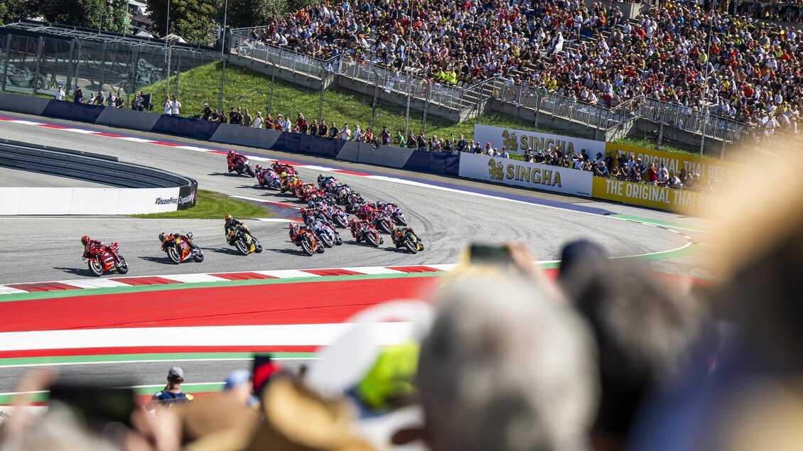 Ein spannendes Motorradrennen auf einer Rennstrecke mit jubelnden Zuschauern. Die Fahrer fahren in einer Kurve mit hoher Geschwindigkeit. | © Lucas Pripfl - Red Bull Ring
