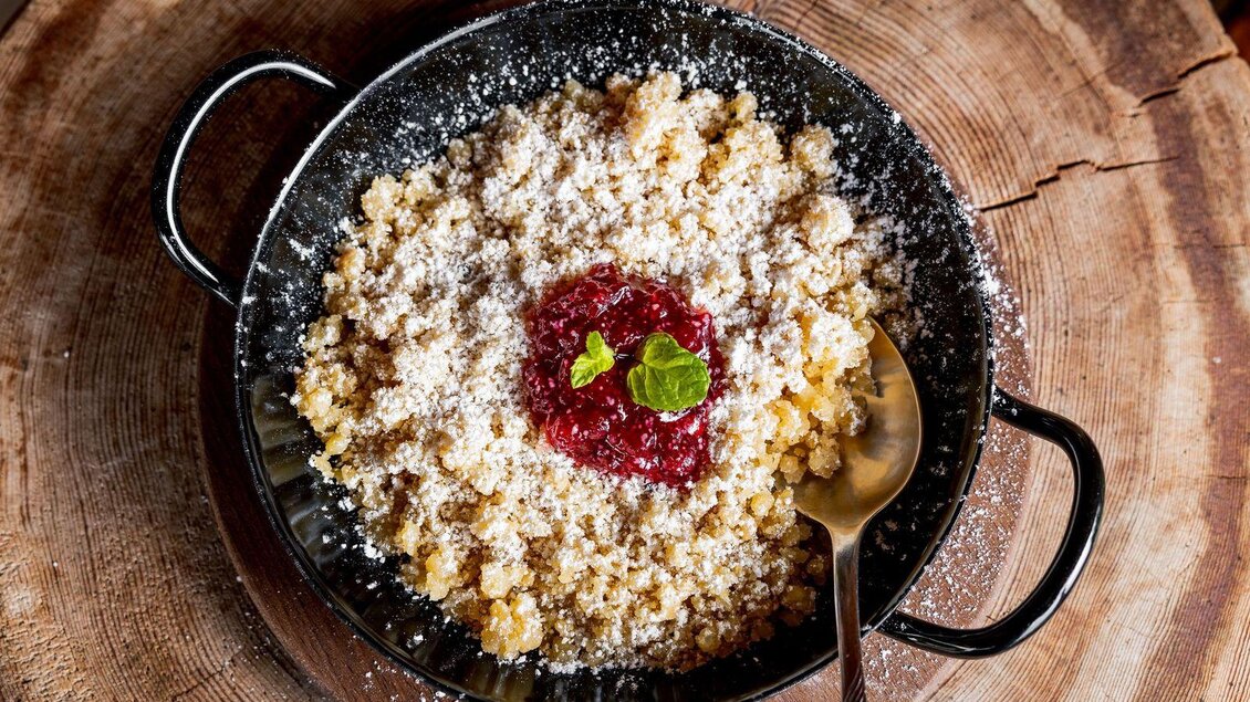 Ein gefüllter Teller mit süßem Grießbrei, bestreut mit Puderzucker und einer Portion Marmelade. Eine frische Minzeblattgarniert das Gericht. | © Martin Huber