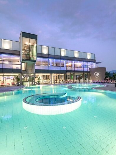 Ein modernes Hotel mit einem großen Pool. Der Pool hat eine runde Whirlpool-Ecke und ist bei Dämmerung beleuchtet. | © Region Graz-Die Abbilderei