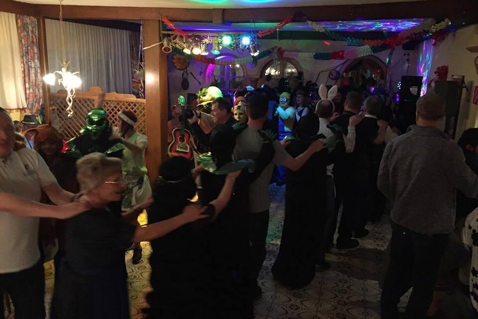 Eine lebhafte Tanzveranstaltung mit vielen Menschen, die in bunten Kostümen feiern. Der Raum ist mit bunten Lichtern dekoriert und es herrscht eine fröhliche Stimmung. | © Gasthof Moser