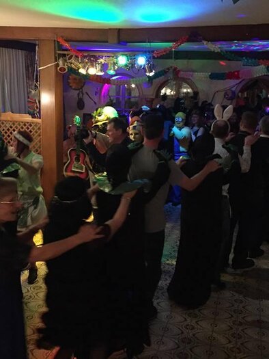 Eine lebhafte Tanzveranstaltung mit vielen Menschen, die in bunten Kostümen feiern. Der Raum ist mit bunten Lichtern dekoriert und es herrscht eine fröhliche Stimmung. | © Gasthof Moser