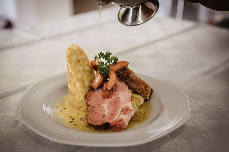 Ein appetitlicher Teller mit zartem Fleisch, Beilagen und einer Sauce. Oben garnieren einige kleine Gemüse und ein Kräuterzweig. | © Martinhof