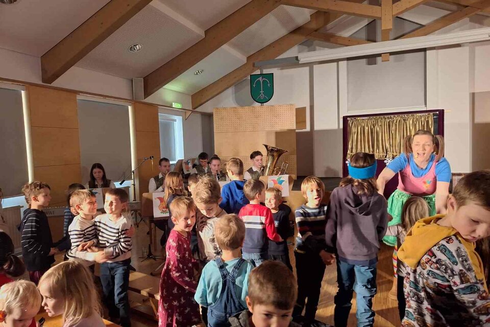 Ein fröhlicher Clown mit einem bunten Hut spielt Saxophon. Er trägt ein buntes Outfit und hat rote Locken. | © Musikverein Stubenberg