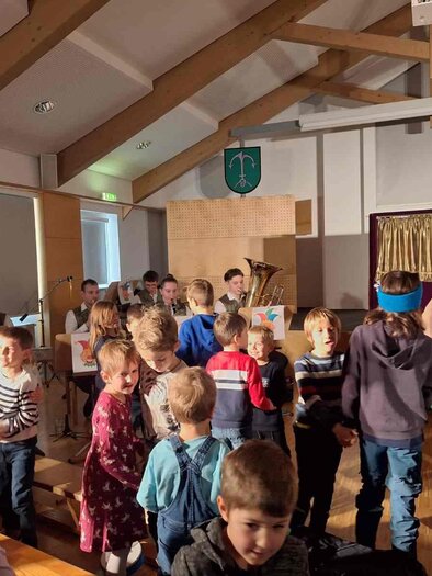 A cheerful clown with a colorful hat plays the saxophone. He wears a colorful outfit and has red curls. | © Musikverein Stubenberg