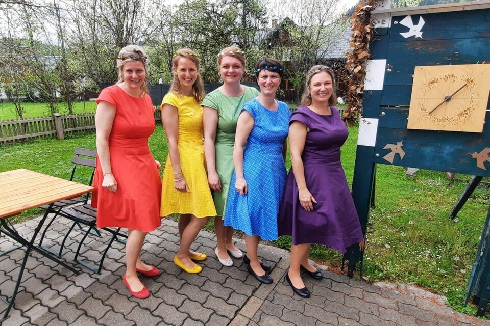 Fünf Frauen in bunten Kleidern stehen lächelnd zusammen. Im Hintergrund sind ein Tisch und eine Gartenlandschaft zu sehen. | © Rainer Fischer