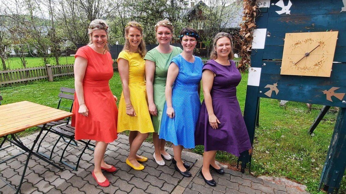 Fünf Frauen in bunten Kleidern stehen lächelnd zusammen. Im Hintergrund sind ein Tisch und eine Gartenlandschaft zu sehen. | © Rainer Fischer