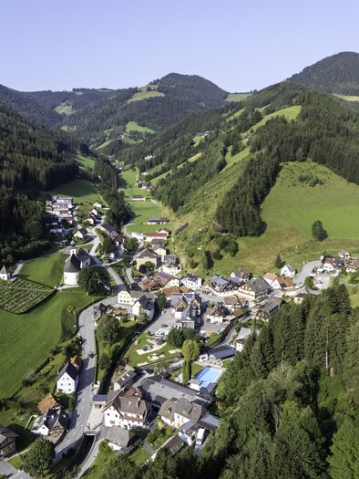 A picturesque village in a green, hilly landscape. Surrounded by forests and mountains, the scene radiates tranquility and idyllic charm. | © Kurt Elmleitner