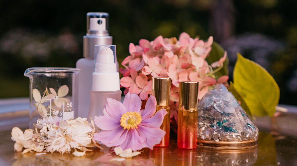 Eine stilvolle Anordnung von Kosmetikprodukten und blühenden Pflanzen. Das Bild zeigt kreative Elemente der Natur, die eine frische und beruhigende Atmosphäre vermitteln. | © Petra Stückelschwaiger