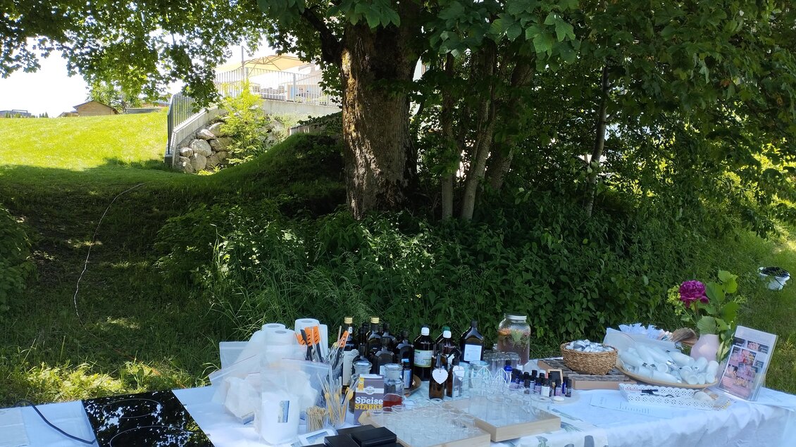 Ein Tisch im Freien, gedeckt mit verschiedenen Flaschen und Produkten. Im Hintergrund stehen Bäume und eine grüne Wiese. | © Petra Stückelschwaiger