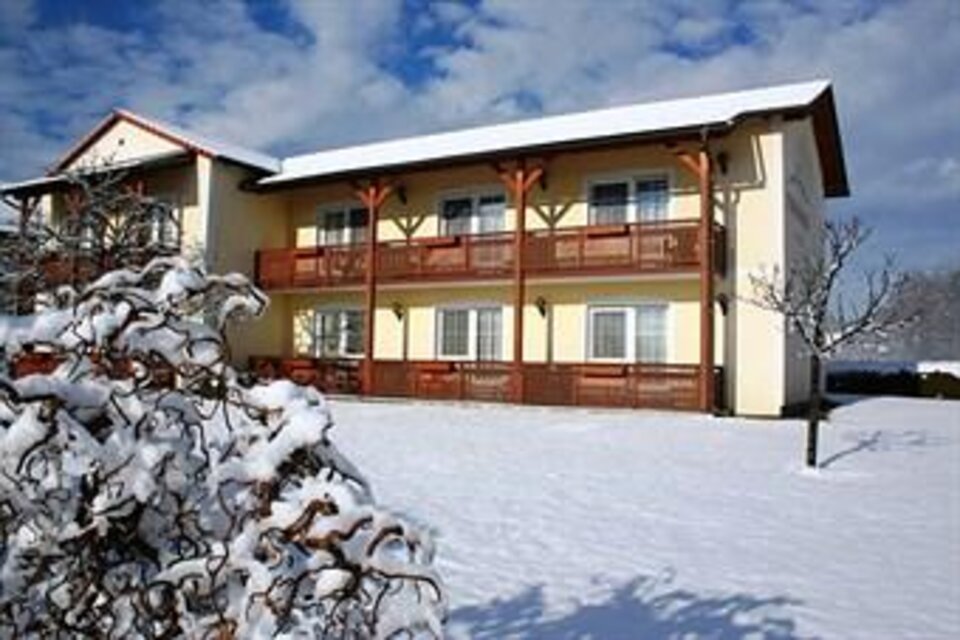 Ein Gebäude im Winter, umgeben von Schnee. Es hat mehrere Balkone und einen klaren Himmel im Hintergrund. | © Teuschler-Mogg