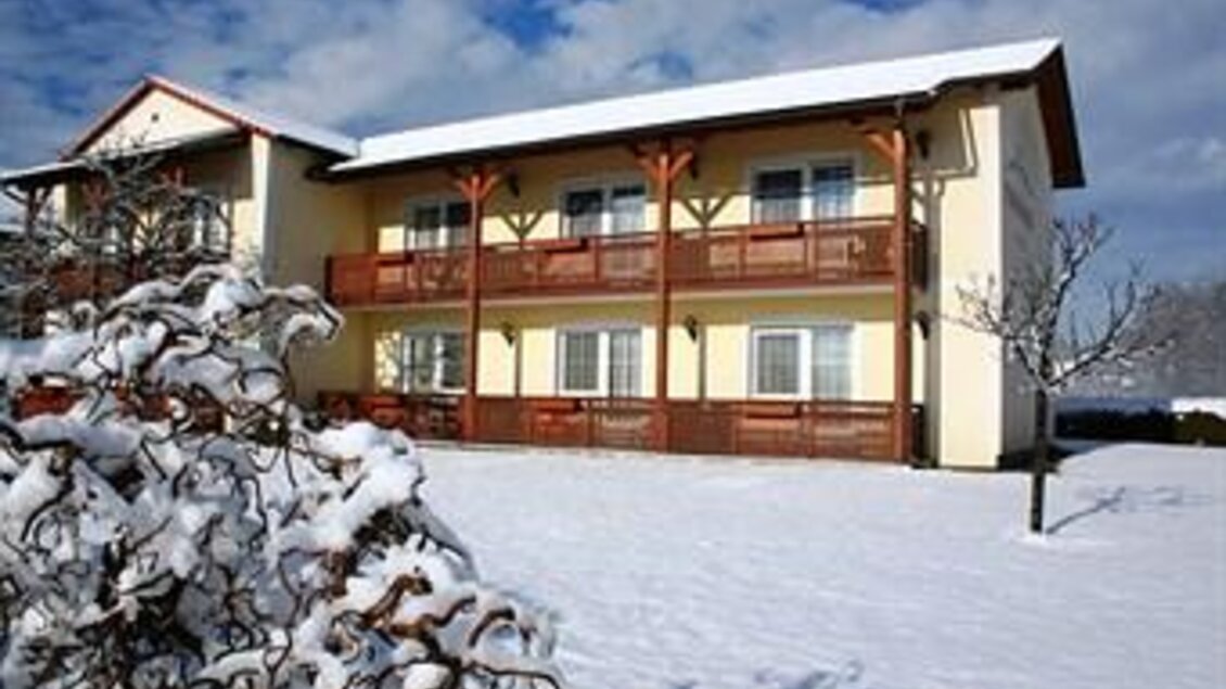 Ein Gebäude im Winter, umgeben von Schnee. Es hat mehrere Balkone und einen klaren Himmel im Hintergrund. | © Teuschler-Mogg