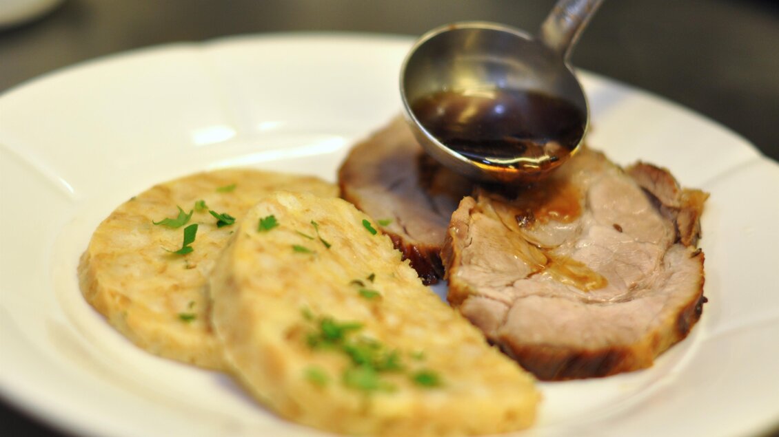 Ein Teller mit zartem Fleisch und zwei Scheiben beigem Beilagen. Darauf wird eine Soße gegossen. | © Teuschler-Mogg