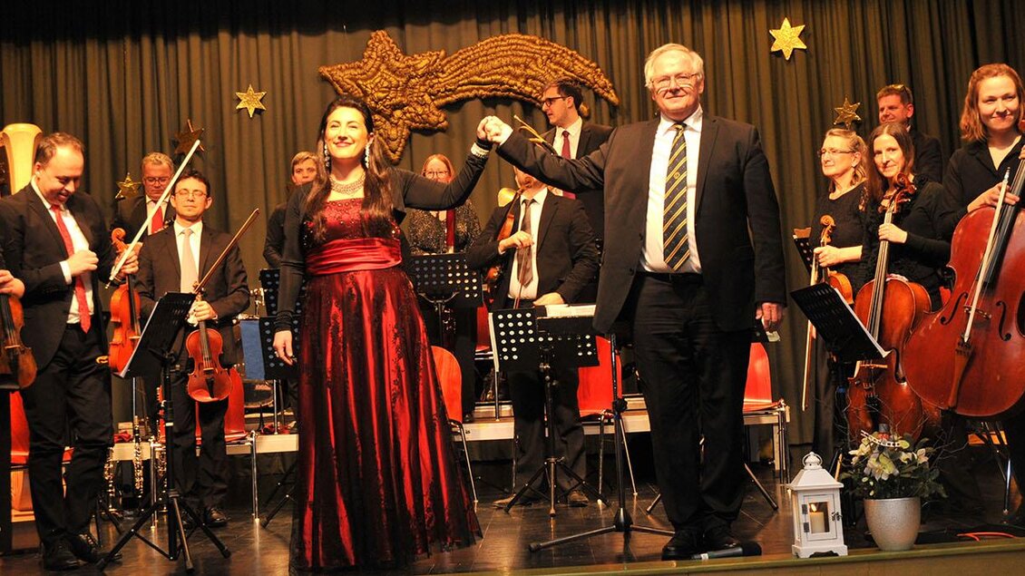 Eine Aufführung mit einem Orchester auf der Bühne. Die Musiker und Sänger stehen gemeinsam vor dem Publikum und feiern ihren Auftritt. | © Siegel Sabine