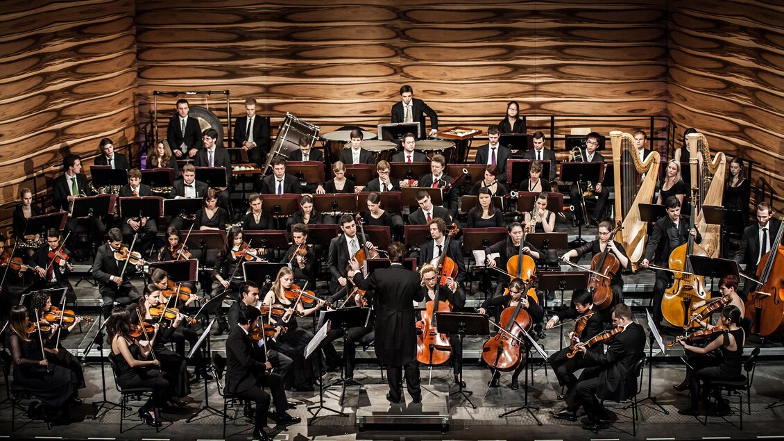 Ein Orchester spielt auf einer Bühne. Der Dirigent leitet die Musiker in einem beeindruckenden Konzert.